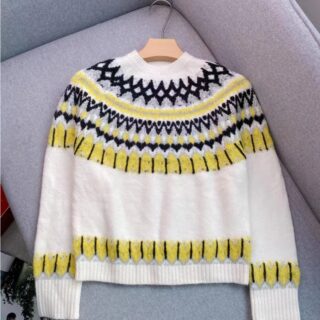 Pull blanc avec un jaquars jaune et noir posé sur un canapé