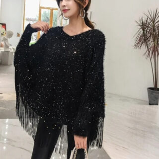 Pull chauve souris col rond noir avec des franges, porté par une femme qui tient son sac