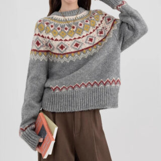 On voit une femme aux cheveux longs et bruns qui porte un pull gris norvégien