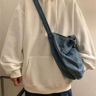 Homme portant un pull blanc oversize et un sac bandoulière bleu.