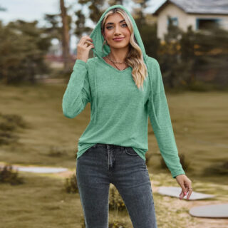 Femme portant un pull vert à capuche et se trouvant dans un jardin.