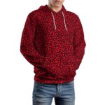 Photo d'un homme debout portant un pull léopard rouge à capuche ajustable ave cordon de serrage sur un jean bleu clair, les mains dans la poche ventrale du pull, le tout sur un fond blanc