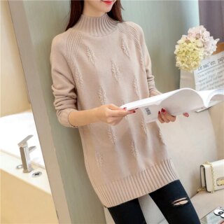 Femme portant un pull long et tenant un livre.