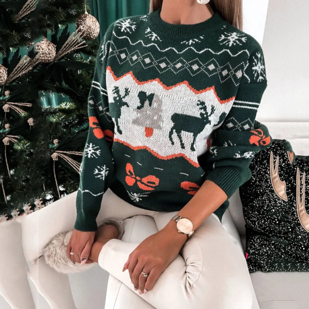 On voit une femme qui porte un pull de noël vert avec des motifs de Noël (rennes, sapins, flocons)