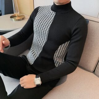 Pull à col cheminé noir et avec des motifs blanc porté par un homme assi dans un canapé