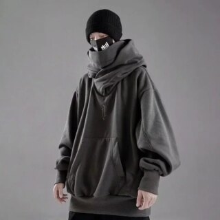 Homme portant un pull oversize et un bonnet sur un fond gris.