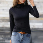 On voit une femme brune qui porte un sous-pull col roulé noir.