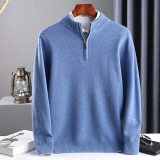 Photo représentant un pull zippé bleu sur une chemise blanche les deux sur un cintre en bois au dessus d'un plan de travail blanc un rideau plissé gris foncé à l'arrière droit et une lampe style lanterne sur la gauche