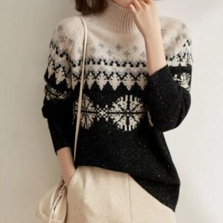 Pull jaquard noir et beige avec des flocons de neige porté par une femme en pantalon beige