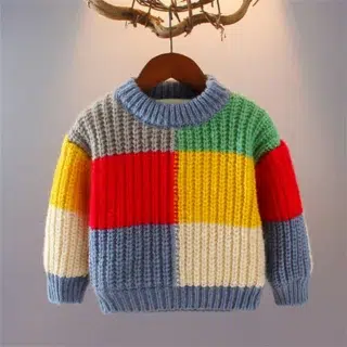On voit un pull pour garçon suspendu à un cintre. Il est de toutes les couleurs comme un patchwork.