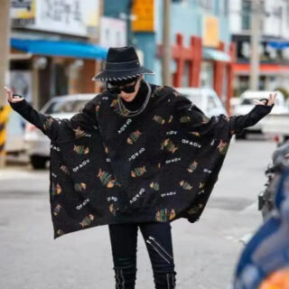 On voit un homme d'origine asiatique qui porte un pull manches chauve souris noir avec des motifs modernes