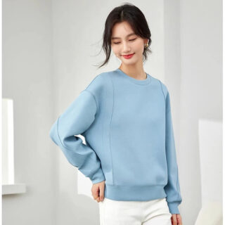 Femme portant un pull bleu sur fond blanc.