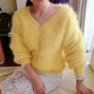 Photo d'une femme assise sur le rebord intérieur d'une fenêtre portant un pull jaune pilou pilou à col V et manches longues sur une jupe blanche en dentelle