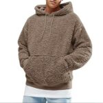 Photo d'un homme portant un pull pilou pilou marron style sweat à capuche ajustable sur un teeshirt blanc et un jean bleu ciel avec les mains dans la poche devant, le tout sur fond blanc