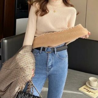 Femme portant un pull beige fourré et un jean bleu.