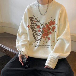 Homme portant un pull blanc avec un papillon et des fleurs.