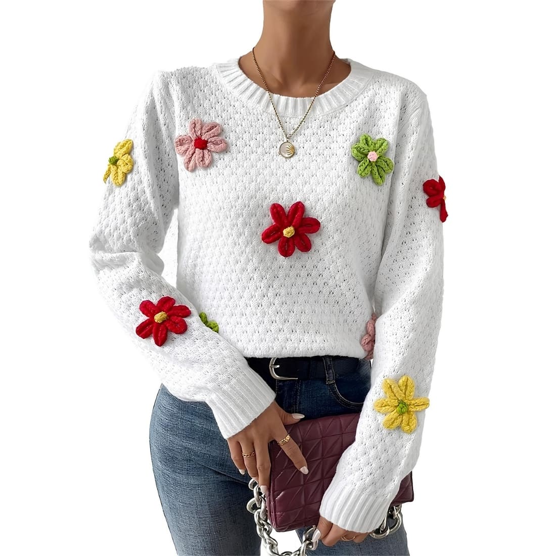 Pull fleuri blanc ample à manches longues et col rond pour femme porté par une femme en jean avec un sac marron dans les mains.