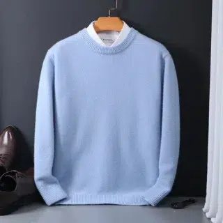 Pull bleu sur fond gris.