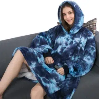 Une femme assise sur un canapé qui porte un grand pull à capuche bleu