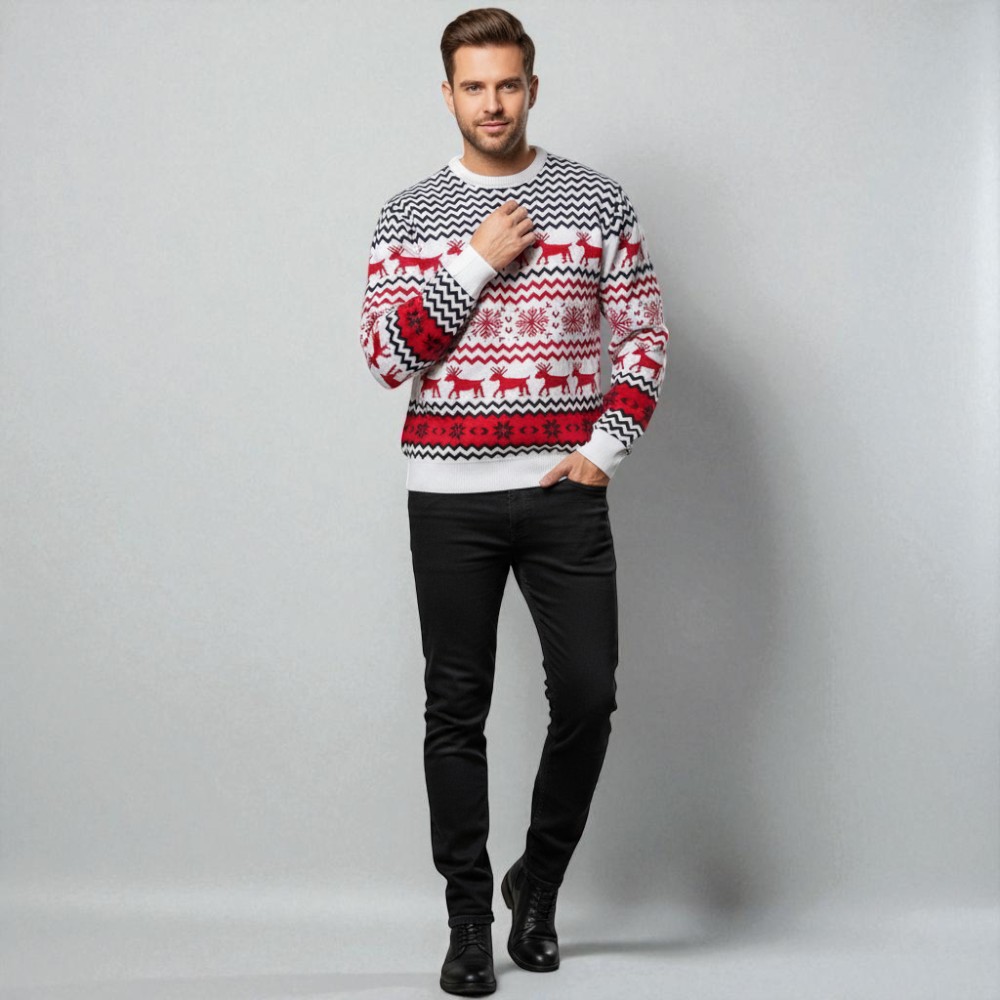 Homme caucasien châtain, se tenant debout et portant un pull de Noël avec motifs rennes et flocons en tricot chaud sur fond gris clair.